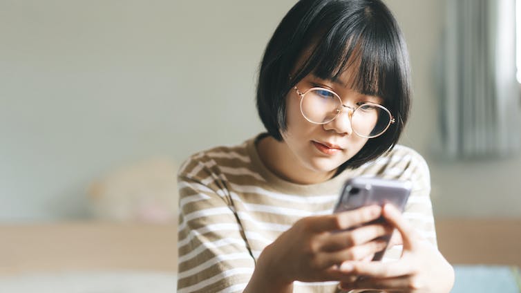 A young woman looking at a smartphone.
